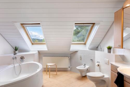 an attic bathroom with a tub and a toilet and a sink at Ferienwohnung Schliestädt in Wellerode