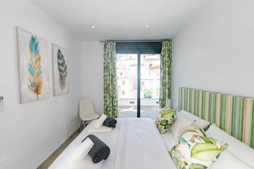 a white bedroom with a bed and a window at Luxury apartment in Cómpeta in Cómpeta
