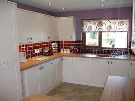 a kitchen with white cabinets and a window at Ty Talcen in Pennal