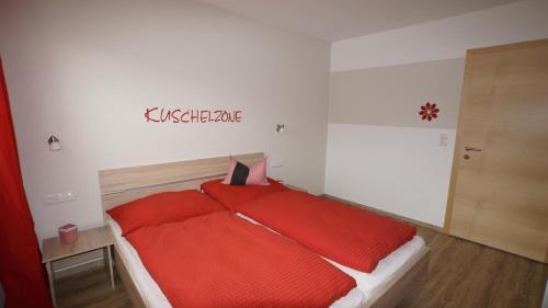 a bedroom with a red bed with a sign on the wall at Ferienwohnung Mario in Hippach