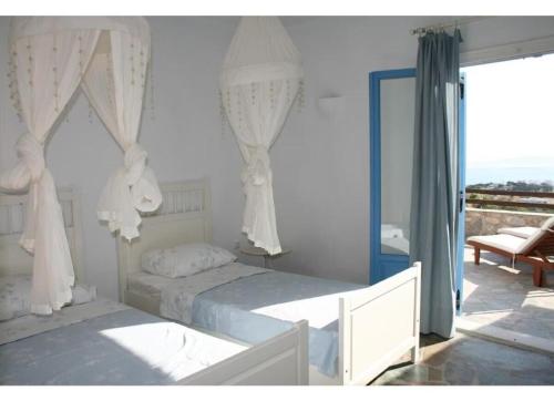 a bedroom with two beds with curtains and a window at Villa Galazio in Kampos Paros