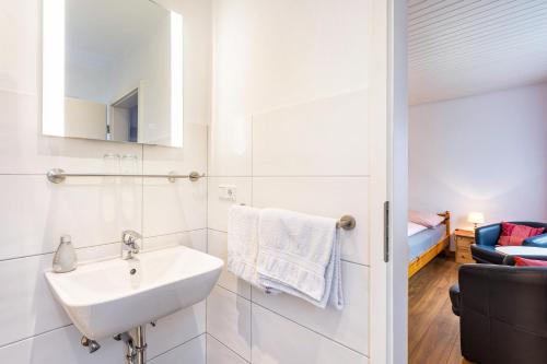 a white bathroom with a sink and a couch at Ferienwohnung Kebben in Kirchhundem