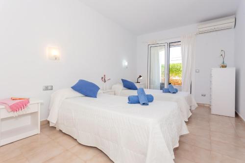 two beds in a room with white walls and blue pillows at Lurdes in Ciutadella