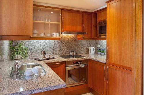 una cocina con armarios de madera y fregadero en Apartamento Torre Gran Luxe en Port de la Selva