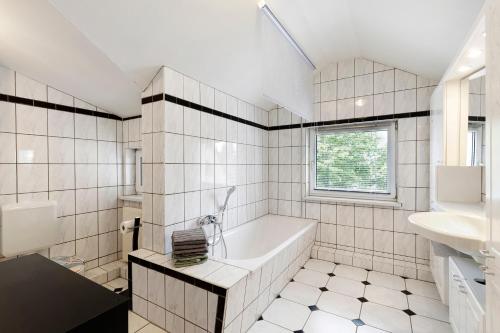 a white tiled bathroom with a tub and a sink at Ferienwohnung in Potsdam in Potsdam