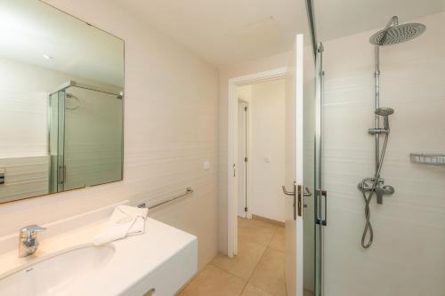 a white bathroom with a sink and a shower at Apartamento Bon Aire N3 in Cala Ferrera