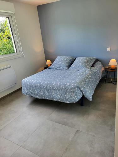 a bedroom with a bed with a blue comforter and a window at Gîte Bord De Mer La Guichardière in Pirou