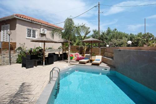 a swimming pool with chairs and umbrellas next to a house at Villa Dionysia Studio 10 in Alikanas