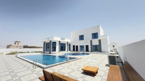 a villa with a swimming pool and a house at Al REEF in Billah