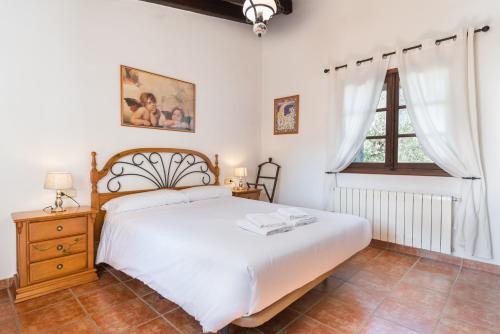 a bedroom with a white bed and a window at Can Llobera in Pollença