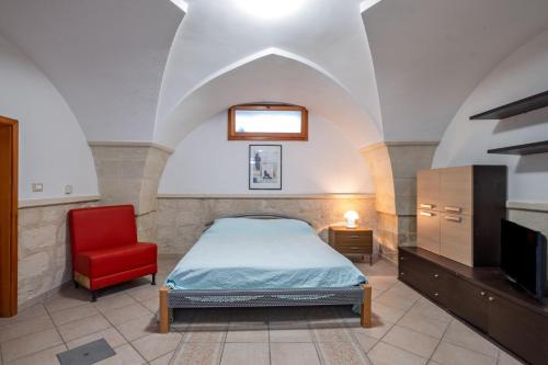 a bedroom with a bed and a red chair at Casa dell'Angelo in Muro Leccese