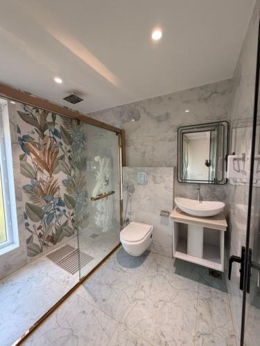 a bathroom with a shower and a toilet and a sink at Ascent Eco Resorts & Conventions in Rājānagaram