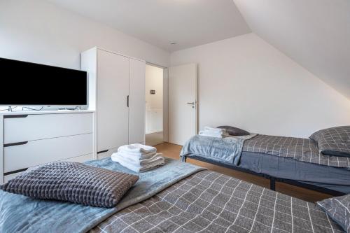 a bedroom with two beds and a flat screen tv at Kroge Apartment in Uelzen