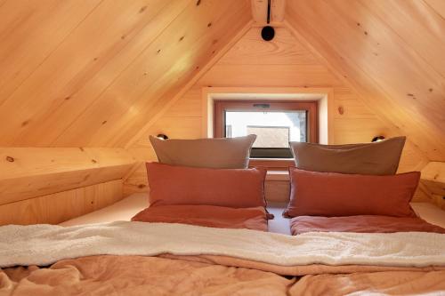 a bed in a wooden room with a window at Schwarzwaldchalet Holzperle in Lenzkirch