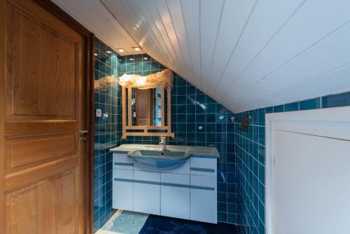 a blue tiled bathroom with a sink and a mirror at Cottage au Calme in Gèdre