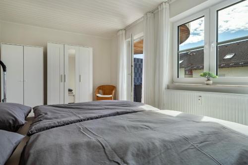 a bedroom with a large bed and two windows at Bodenseenest in Meckenbeuren