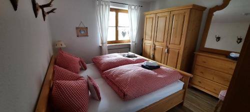 a bedroom with two beds with red sheets and a window at Chaletwohnung Alpenglück in Burgberg
