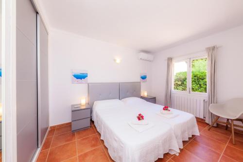 a white bedroom with a white bed and a window at Bona Mar in Cala Ratjada
