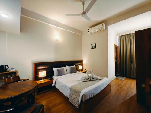 a bedroom with a bed and a desk and a table at Hotel Tragopan in Dimāpur