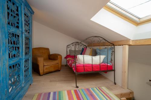 a bedroom with a bed and a chair and a window at Le Balcon des Bauges in La Motte-Servolex
