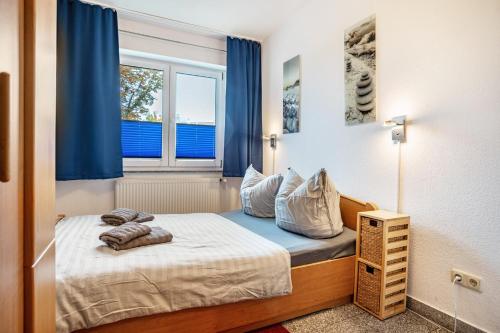 a small bedroom with a bed with blue curtains at Haus Frohsinn - Wohnung 3 in Binz