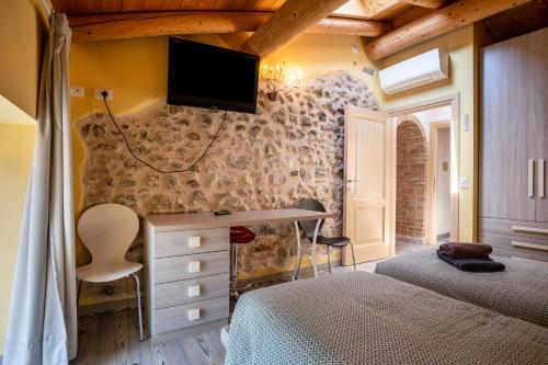 a bedroom with two beds and a desk with a tv on the wall at Appartamento Gufo in Tremosine Sul Garda