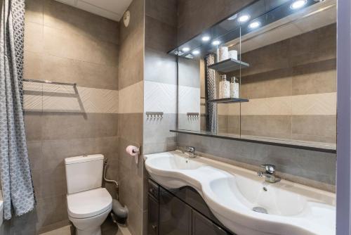 a bathroom with a sink and a toilet and a mirror at Appartement des Cedres in Uzès