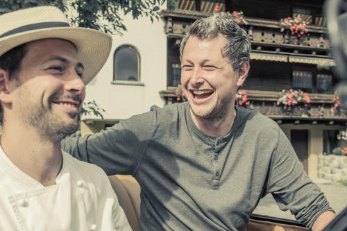 two men laughing while sitting next to each other at Aktiv-Ferienwohnungen Montafon in Sankt Gallenkirch