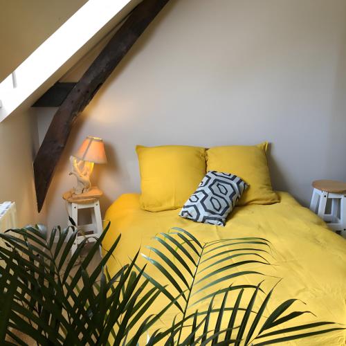 a bedroom with a yellow bed with two pillows at Gîte Bonaty in Soulgé-sur-ouette