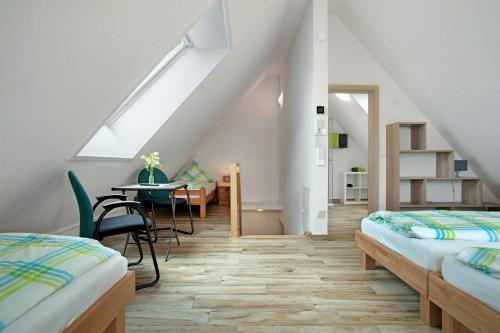 a attic room with two beds and a table and a dining room at Biohof Stotz in Friedrichshafen