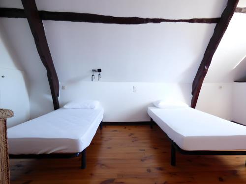 two beds in a room with white walls and wooden floors at Gite De La Guillone in Savignac