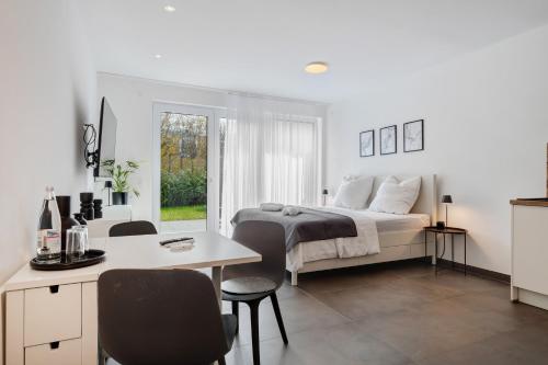 a white bedroom with a bed and a table and chairs at Apartment Aura in Mengen