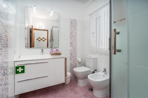 a white bathroom with a toilet and a sink at Villa Raposo em Porches in Porches