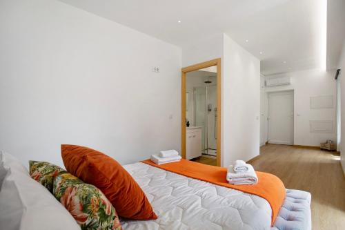a bedroom with a bed with an orange blanket on it at Moradia dos Castelos Amarelo in Santarém