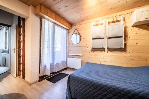 a bedroom with a bed in a wooden room at Appt bien agencé, bien placé-Châtel in Châtel