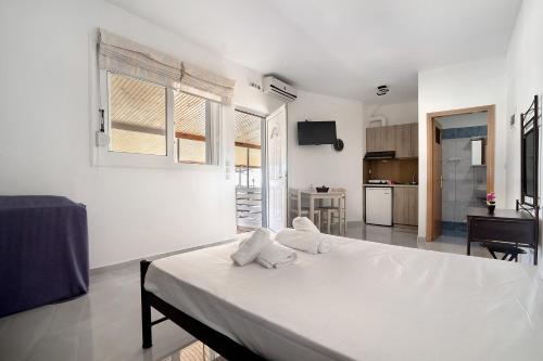 a white bedroom with a bed and a kitchen at Iguana studio 12 in Preveza