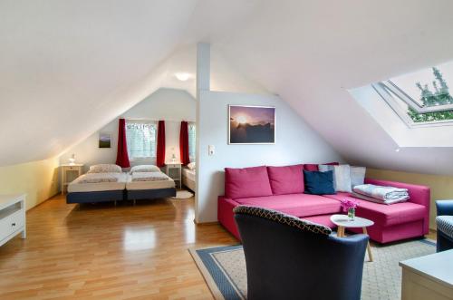 a living room with a pink couch and a bed at Landhüsli Illmensee in Illmensee