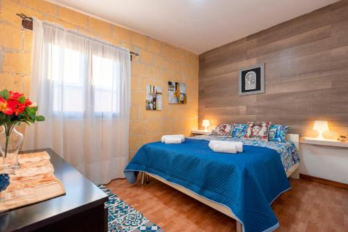 a bedroom with a blue bed and a window at Villa Ina in Cinisi