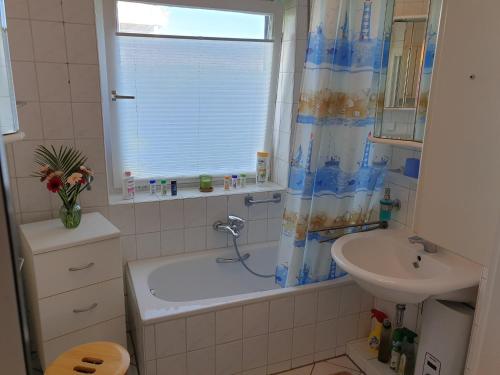 a bathroom with a tub and a sink and a window at Ferienwohnung Strandperle-Schilksee in Schilksee