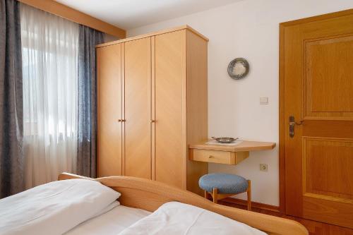 a bedroom with a bed and a cabinet and a chair at Mayr Apartments Fünf in Plaus