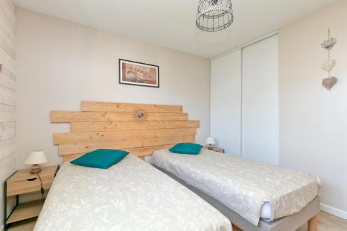 two beds in a bedroom with white walls at Gîte Le Champ Du Bois in Missillac