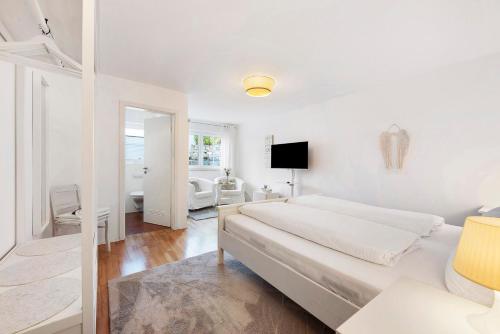 a white bedroom with a bed and a living room at Privatzimmer Kippenhausen in Immenstaad am Bodensee