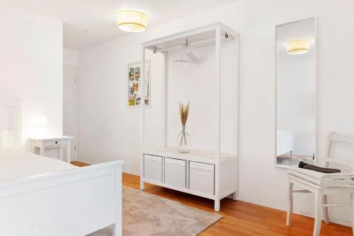 a white bedroom with a bed and a mirror at Privatzimmer Kippenhausen in Immenstaad am Bodensee