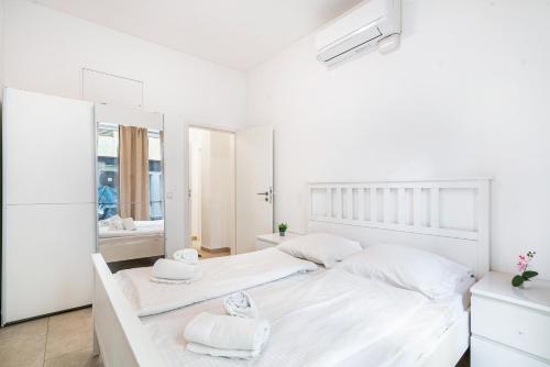 a white bedroom with two beds and a mirror at Aldars Urban Trio Suite Nr. 9 in Munich