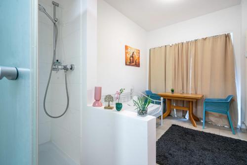 a bathroom with a shower and a table with blue chairs at Aldars Urban Trio Suite Nr. 9 in Munich
