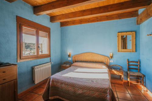 a blue bedroom with a bed and a window at El Pico Llanillo in San Miguel del Arroyo