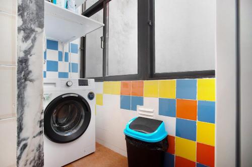 a washing machine in a bathroom with a colorful tile wall at Apartamento da Alegria in Caldas da Rainha