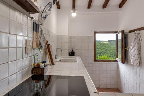 a white tiled bathroom with a sink and a window at Tenuta Acquabona - intero casale in Gambassi Terme