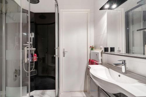 a white bathroom with a shower and a sink at Appartement tout confort in Willstätt