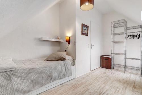 a white bedroom with a bed and a shelf at Appartement tout confort in Willstätt